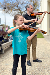 string instructor and student playing string instrument outside